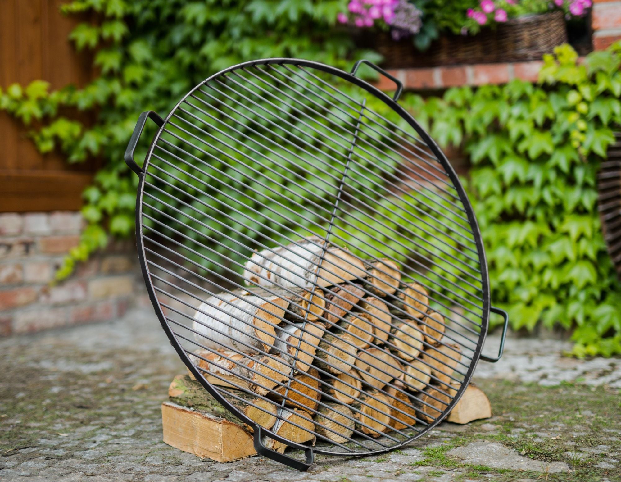 Cook King 60 cm Natural Steel Grate with 4 Handles For Fire Bowl in an outdoor setting