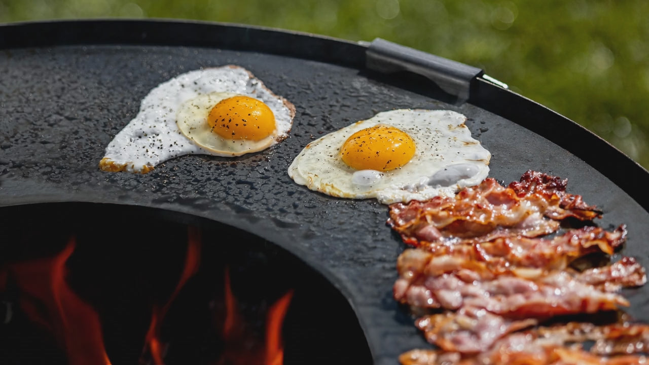 Cook King 82 cm Grill Plate for Fire Bowl with 37 cm Grate cooking on the grill plate over an open fire